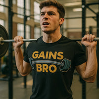 A person is lifting a barbell in a gym setting. They have short brown hair and are wearing a black T-shirt with the text 