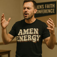 A person with short hair and a beard is wearing a black T-shirt with the text 