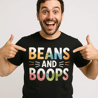 A person is smiling widely and pointing at their black t-shirt with colorful text that reads 