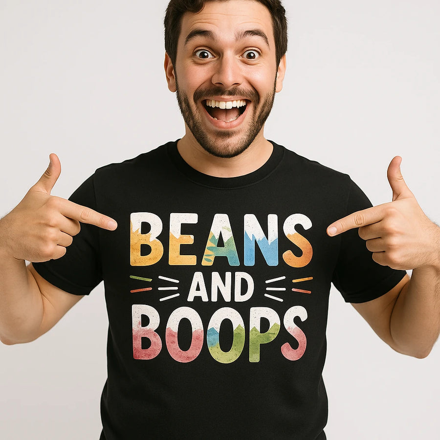 A person is smiling widely and pointing at their black t-shirt with colorful text that reads "BEANS AND BOOPS."