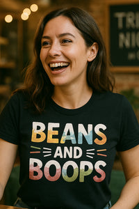 A person with long, dark hair is smiling broadly. They are wearing a black shirt with colorful text that reads 