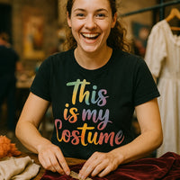 A person is smiling and working on some fabric at a table. They are wearing a black t-shirt with colorful text that reads 