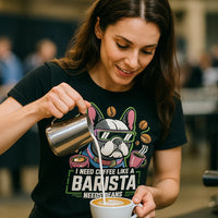 A person with long brown hair is pouring milk into a cup of coffee, creating latte art. They are wearing a black T-shirt with a cartoon image of a dog wearing sunglasses, surrounded by coffee cups and coffee beans.