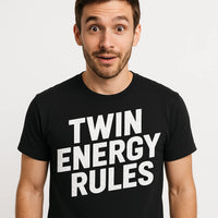 A surprised-looking person with short hair and a beard, wearing a black T-shirt with bold white text. The background is plain white.