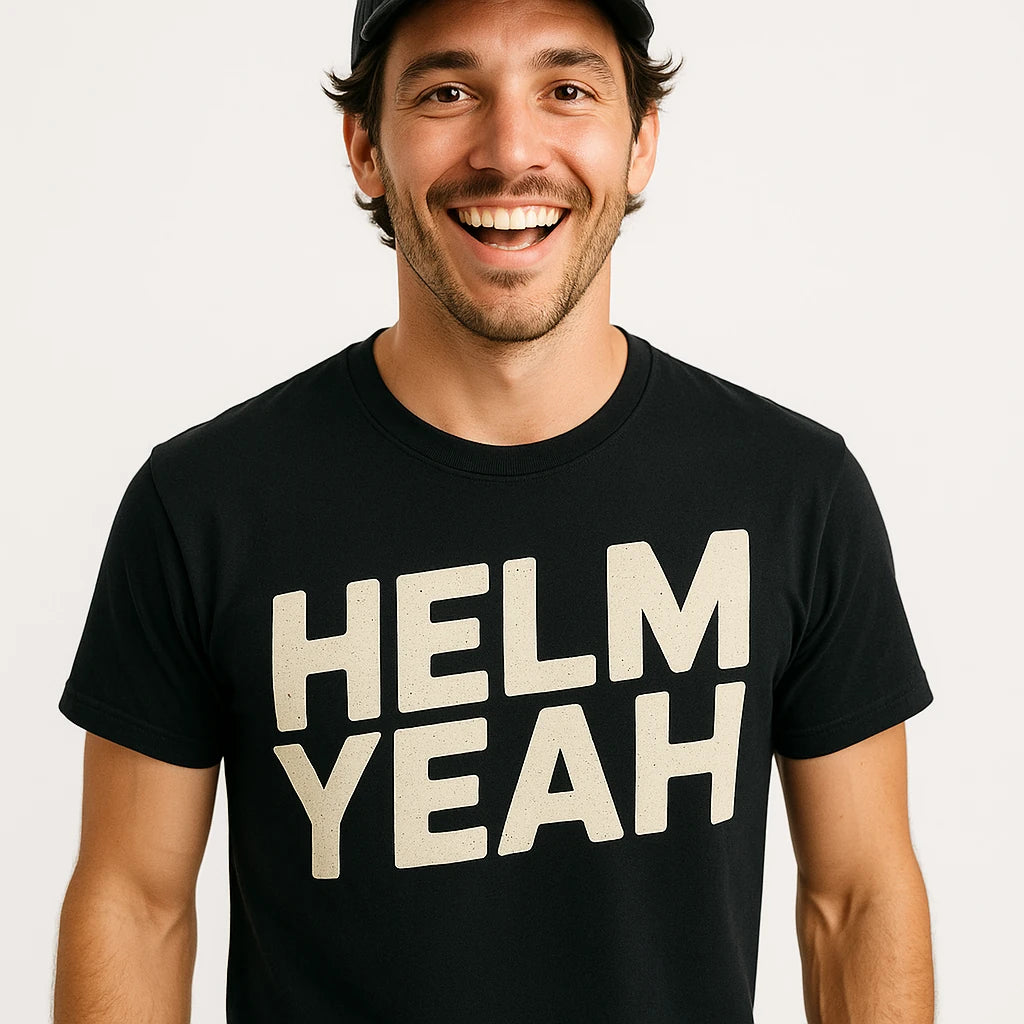 Close-up of the "Helm Yeah" beige print on a premium Bella+Canvas black sailboat t shirt