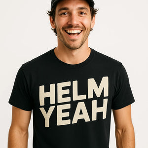 Close-up of the "Helm Yeah" beige print on a premium Bella+Canvas black sailboat t shirt