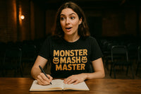 A person with long brown hair is sitting at a wooden table in a dimly lit room with rows of chairs in the background. They have an expression of surprise or excitement and are holding a pen, poised to write in a notebook. They are wearing a black t-shirt with the text 
