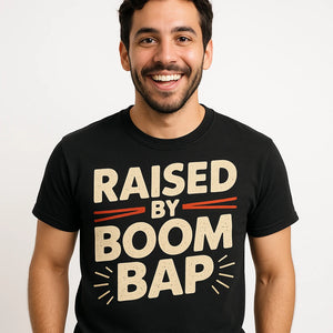 Close-up of the "Raised By Boom Bap" beige print on a premium Bella+Canvas black hip hop tshirt