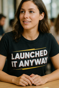 A person with shoulder-length brown hair wearing a black t-shirt with the text 