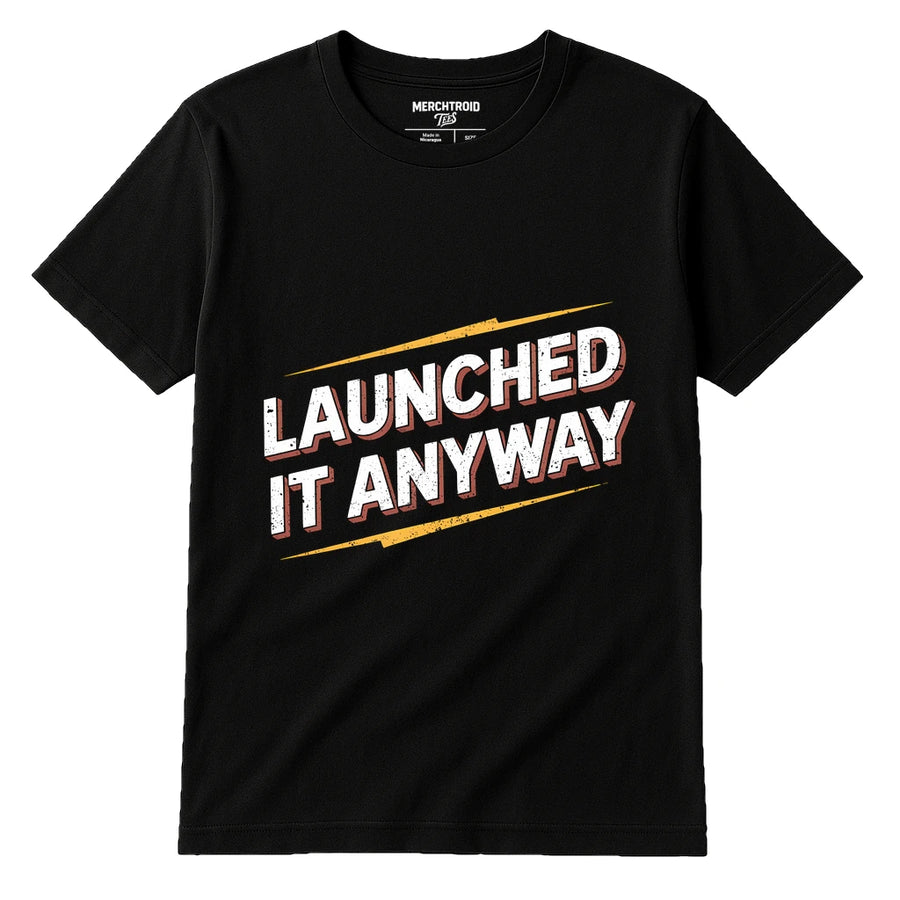 A black t-shirt with bold, distressed white text outlined in red and yellow that reads "LAUNCHED IT ANYWAY." The shirt's collar tag reads "MERCHTROID."