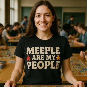 Lifestyle shot of the "Meeple Are My People" black board game tshirts in a real-world setting
