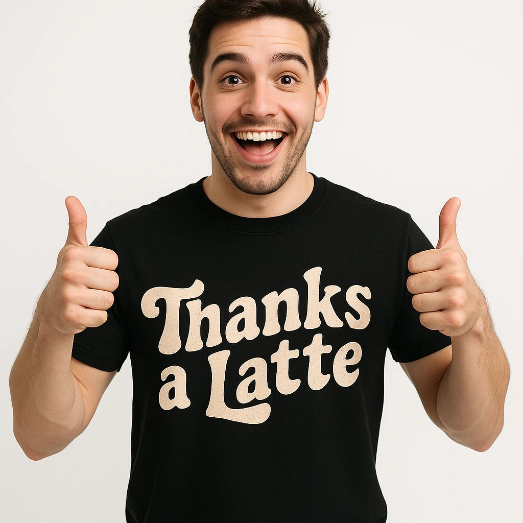 A person with short dark hair giving a thumbs up with both hands. They are wearing a black t-shirt with the text "Thanks a Latte" printed on it. The person is smiling broadly and appears enthusiastic.
