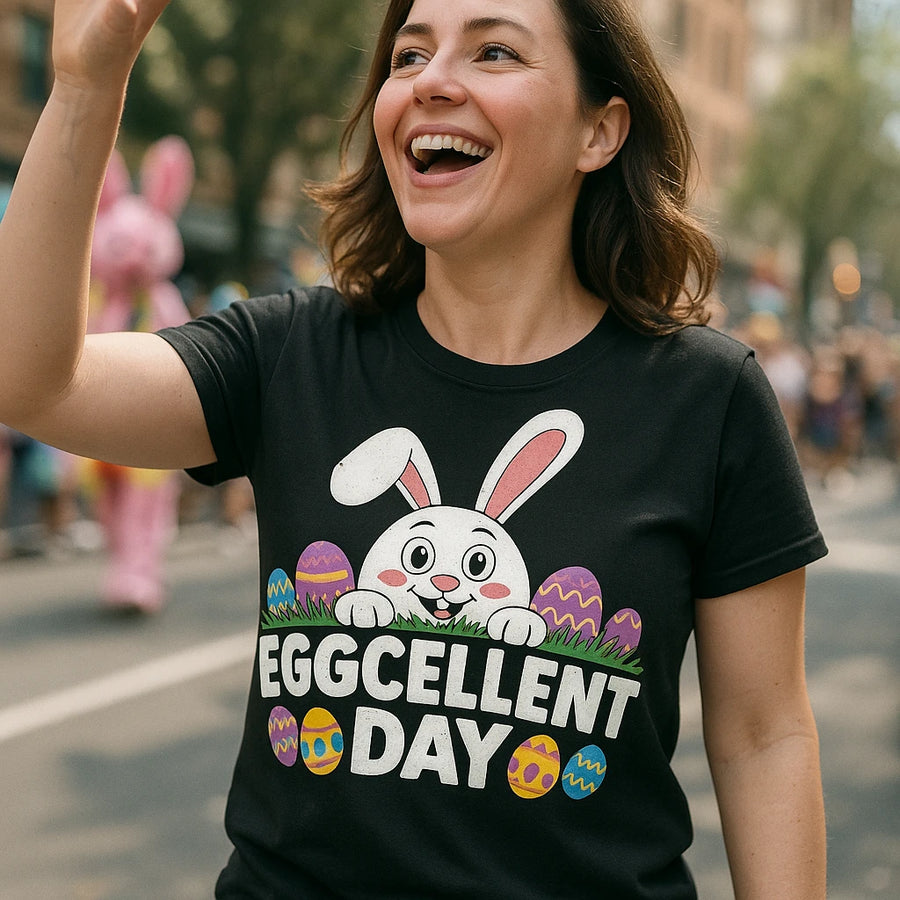 A person is joyfully walking outdoors wearing a black t-shirt featuring a cute white bunny peeking over colorful Easter eggs. The words "EGGCELLENT DAY" are printed underneath. The background shows a blurred street scene with people and a person in a pink bunny costume.