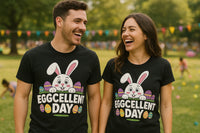 A man and a woman are standing outdoors in a park, laughing together. Both are wearing black t-shirts with a design of a cartoon bunny surrounded by colorful Easter eggs and the words 