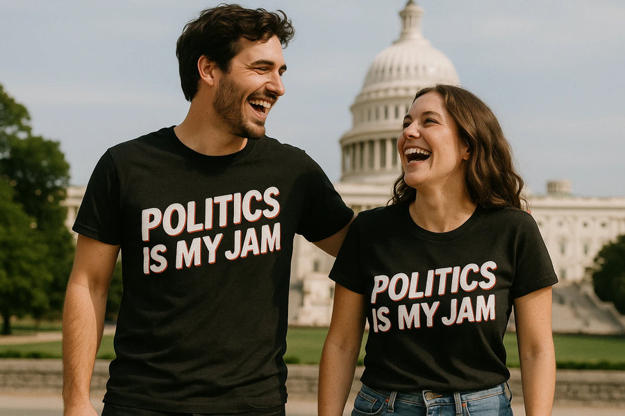 A man and woman are smiling and laughing while wearing matching black T-shirts that read "POLITICS IS MY JAM" in bold letters. They are standing outdoors with the United States Capitol building in the background.