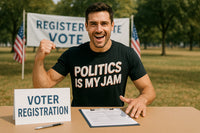 A person sitting at a table outdoors, wearing a black t-shirt with the text 