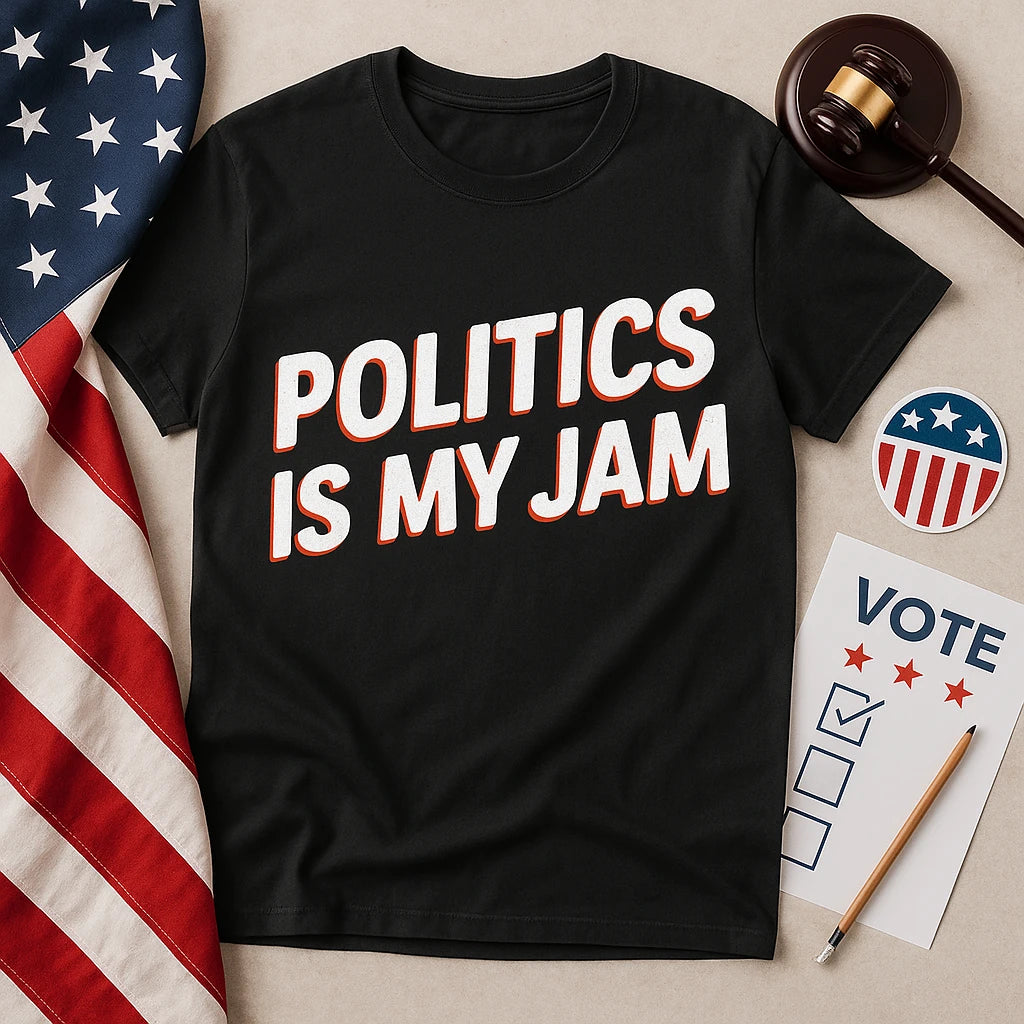 A black t-shirt with the text "POLITICS IS MY JAM" in bold white and red letters is laid on a flat surface. Next to it are a gavel, a pencil, a sheet with the word "VOTE" and checkboxes, a circular sticker with stars and stripes, and an American flag.