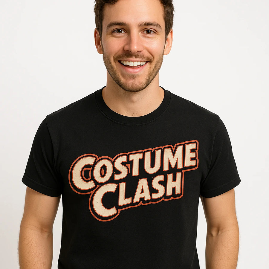 A person with short dark hair and facial hair is smiling at the camera. They are wearing a black t-shirt with the text "Costume Clash" printed on it in bold, stylized letters. The background is plain white.