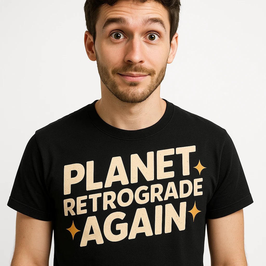 A person wearing a black t-shirt with the text "PLANET RETROGRADE AGAIN" in bold letters. The person has short hair and a beard, and they are looking directly at the camera with a slight smile. The background is plain white.