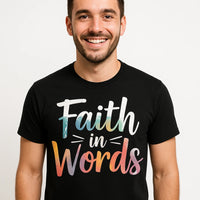 A person with short dark hair and facial hair is smiling and wearing a black T-shirt with colorful text that reads 