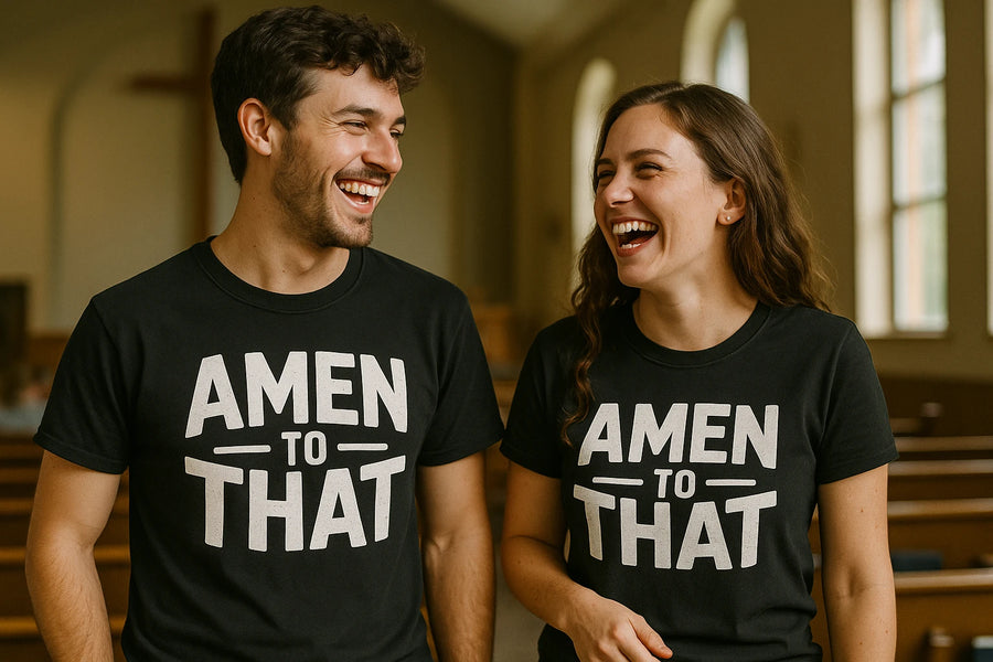 A man and a woman are standing in a church, both wearing black T-shirts with the phrase "AMEN TO THAT" printed in bold white letters. They are smiling and looking at each other with visible joy. The background shows rows of pews and tall windows, giving the space a church-like ambiance.