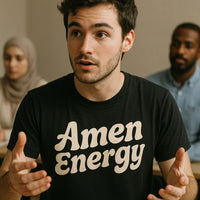 A person with dark hair and a beard is wearing a black T-shirt with the text 