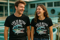 A man and a woman stand outside, both laughing and looking at each other. They are wearing matching black T-shirts with an illustration of a fish and the text 