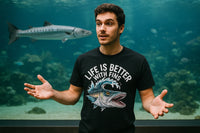 A person stands in front of a large aquarium tank, wearing a black T-shirt with a graphic of a fish and the text 