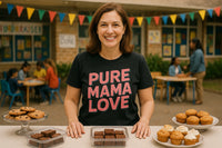 A woman is standing behind a table with assorted baked goods, including cookies, brownies, and muffins. She is wearing a black t-shirt with the text 