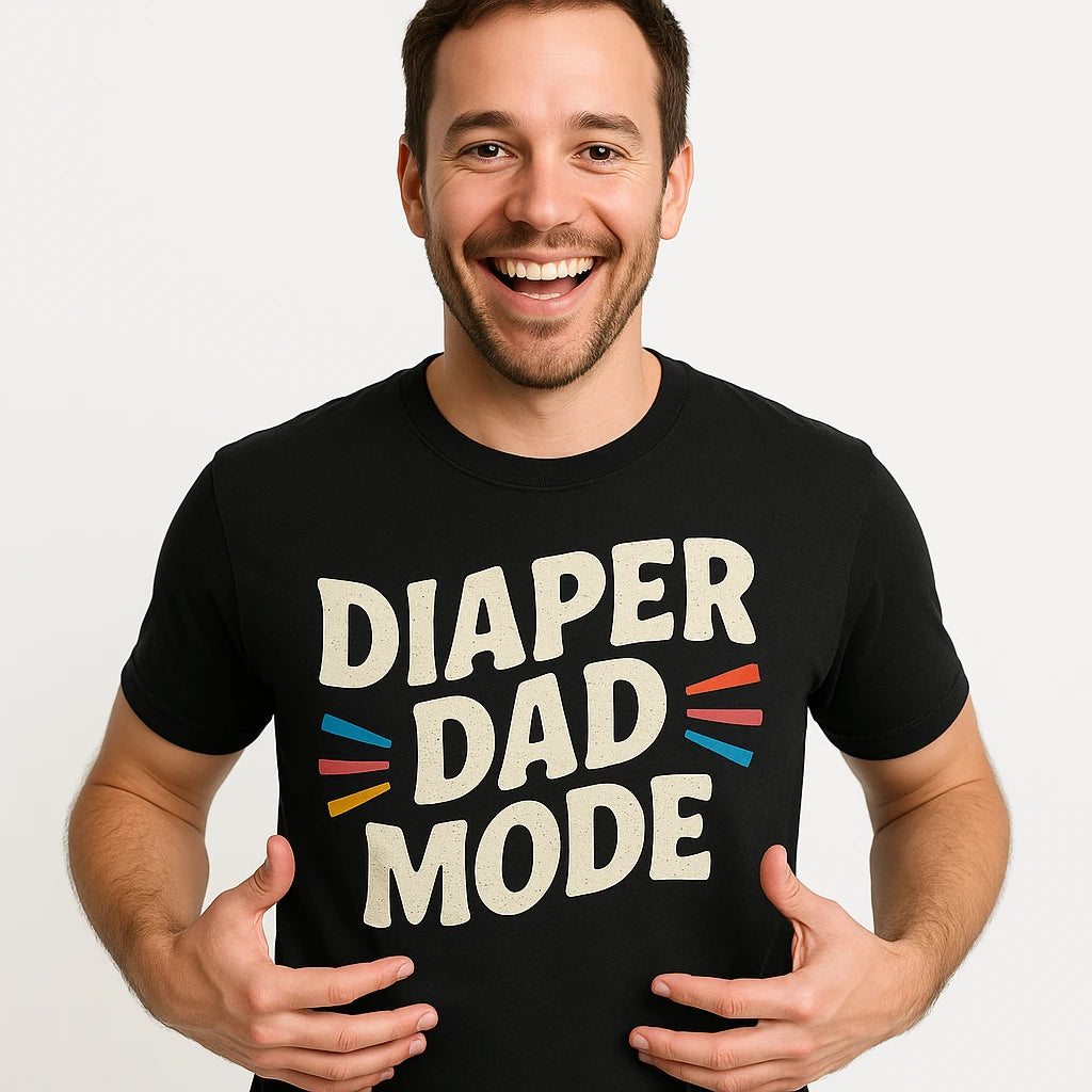 Close-up of the "Diaper Dad Mode" beige print on a premium Bella+Canvas black diaper duty shirts