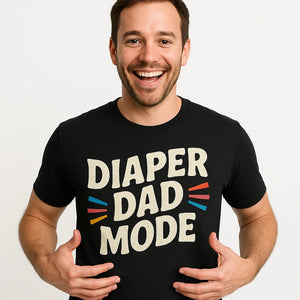 Close-up of the "Diaper Dad Mode" beige print on a premium Bella+Canvas black diaper duty shirts