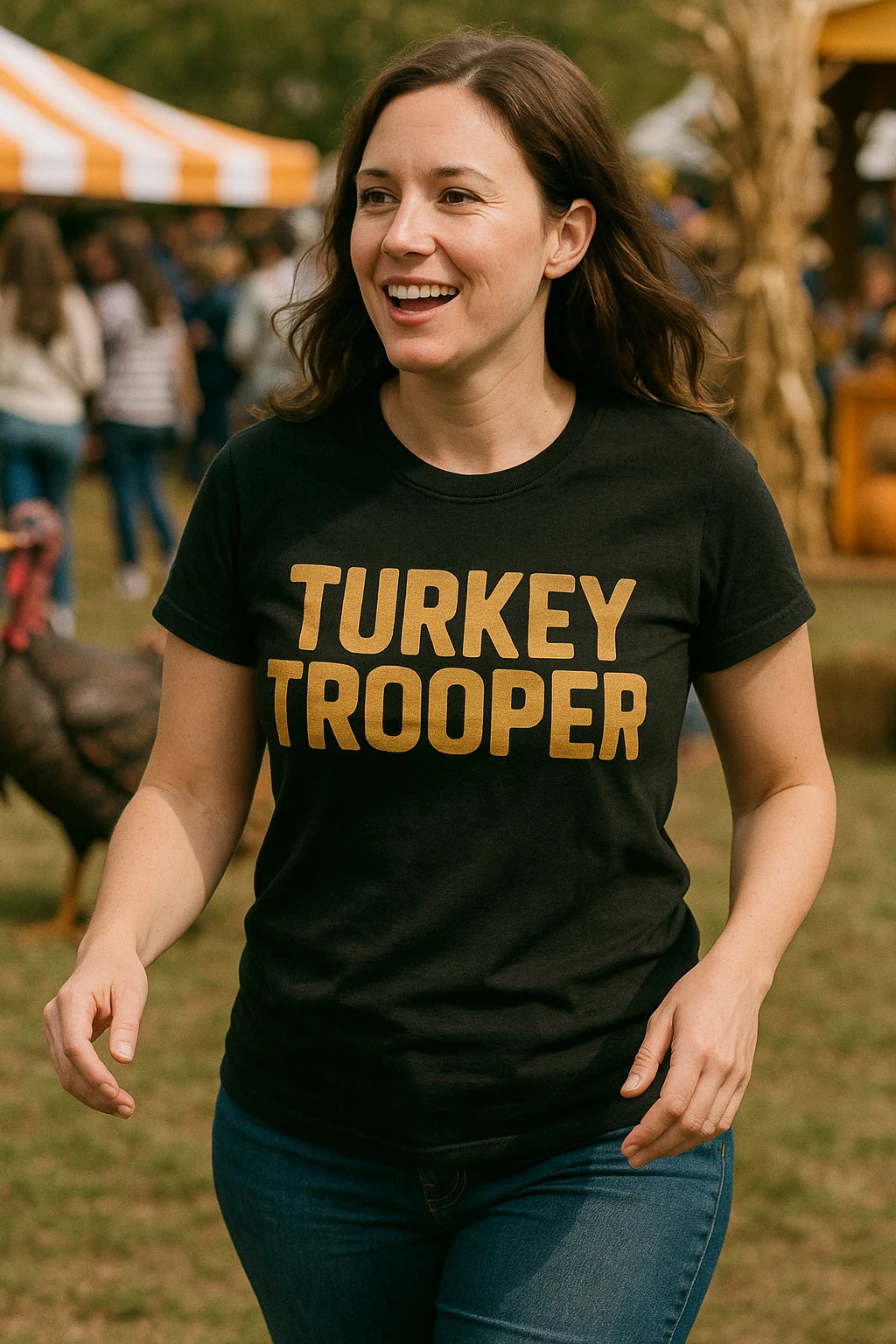 A person with long brown hair is wearing a black T-shirt with the text "TURKEY TROOPER" in bold, gold letters. They are smiling and walking outdoors in a lively area, with other people and a turkey in the background.