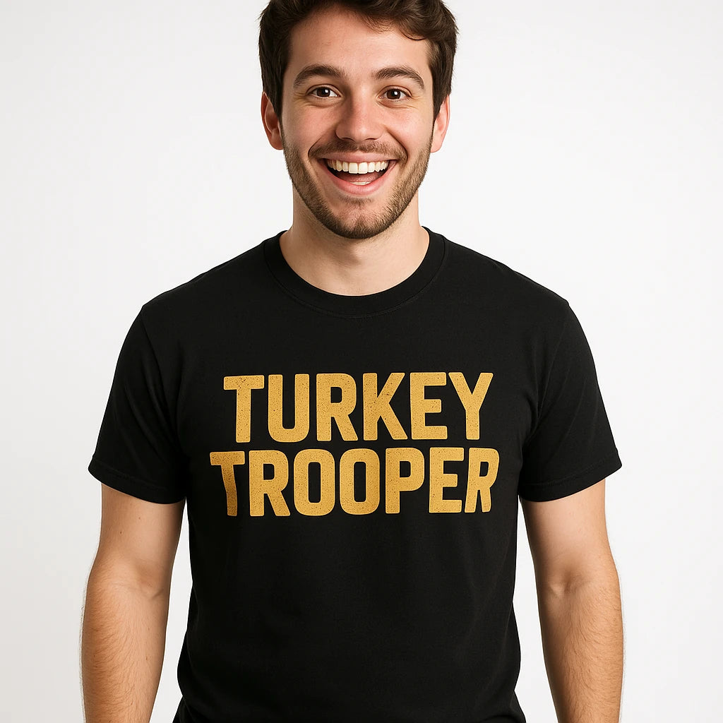 A smiling person with short dark hair is wearing a black T-shirt with the text "TURKEY TROOPER" in bold, gold letters. The background is plain and white.