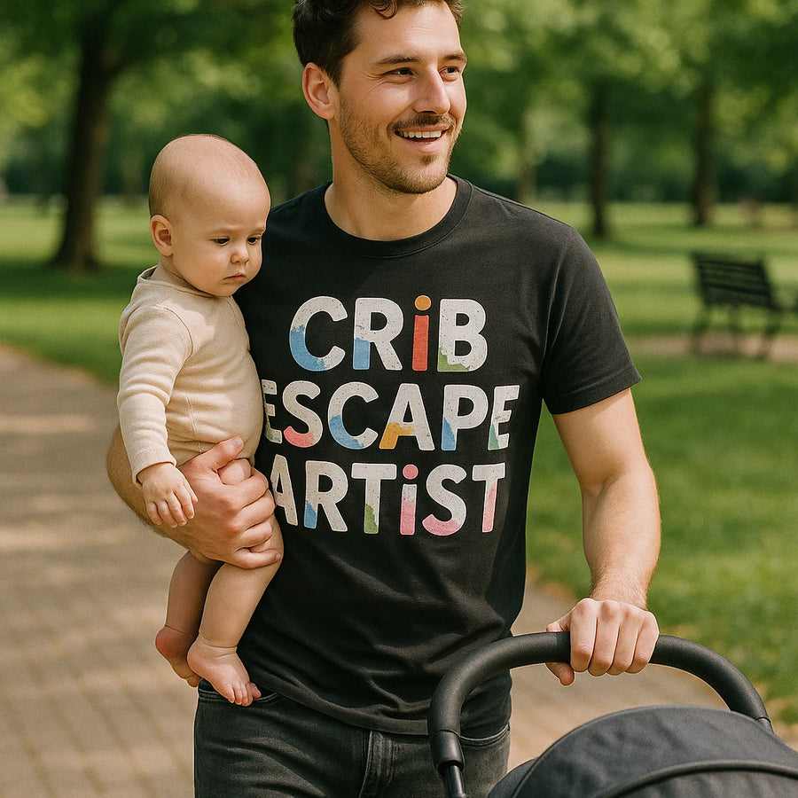 A person is walking in a park while holding a baby in one arm and pushing a stroller. They are wearing a black T-shirt with colorful text on it. The background features greenery and a park bench.