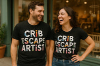 A man and a woman are standing outside, both wearing black t-shirts with colorful block letters that read 