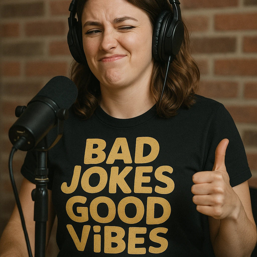 A person wearing headphones and a black shirt with the text "BAD JOKES GOOD VIBES" gives a thumbs-up while sitting in front of a microphone. They have a winking expression, and there is a brick wall in the background.