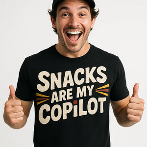 Close-up of the "Snacks Are My Copilot" cream print on a premium Bella+Canvas black adventure t shirt