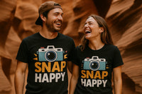 A smiling man and woman stand side by side wearing matching black T-shirts with colorful camera graphics and the text 