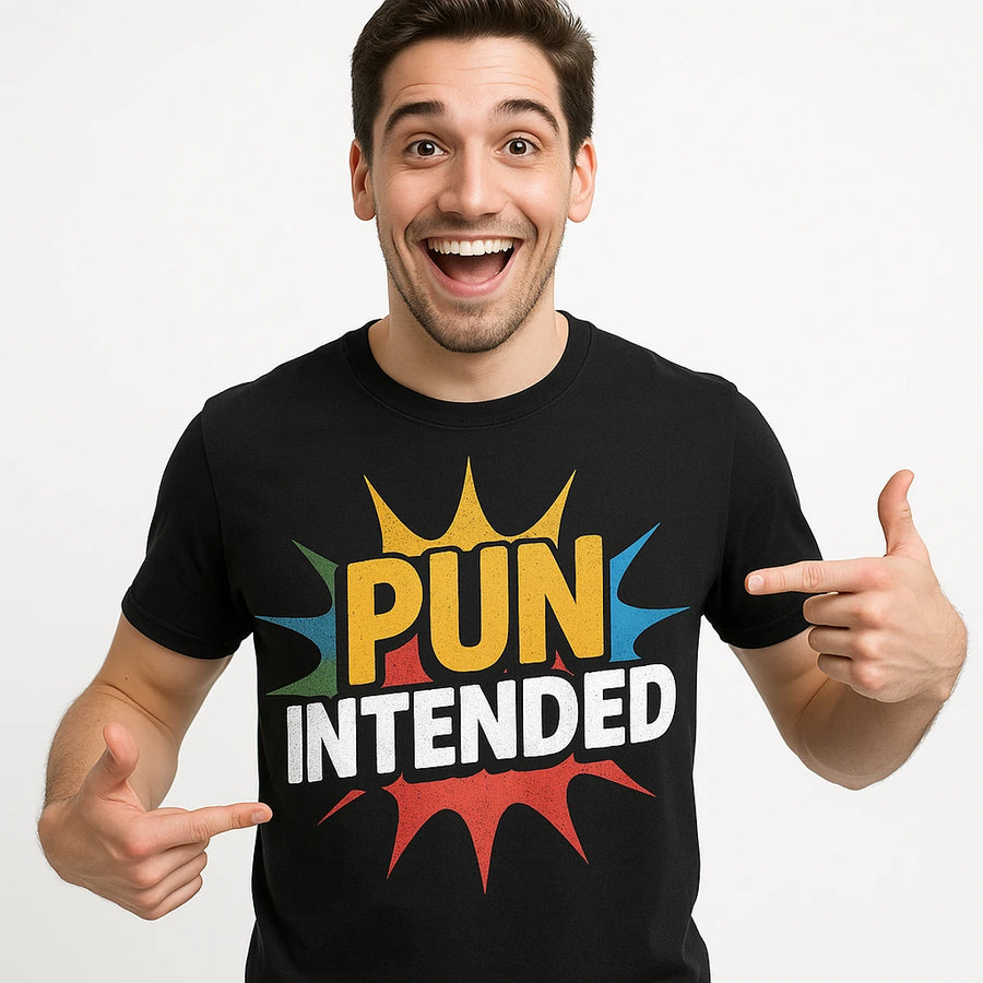 A person with short dark hair is smiling broadly and pointing to their black t-shirt, which has the words "PUN INTENDED" in colorful letters.