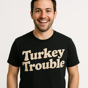 Close-up of the "Turkey Trouble" beige print on a premium Bella+Canvas black thanksgiving tees