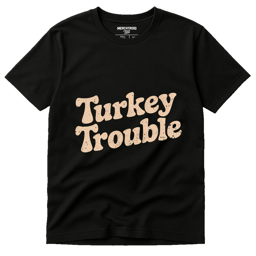 A black t-shirt with the phrase "Turkey Trouble" printed in a large, cream-colored, textured font on the front. The shirt appears new and is displayed against a plain background.