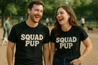 A man and a woman are standing side by side, both wearing black T-shirts with the text 