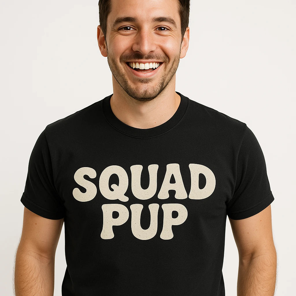 A smiling person with short dark hair and facial hair is wearing a black T-shirt with the words "SQUAD PUP" printed in large, bold white letters.
